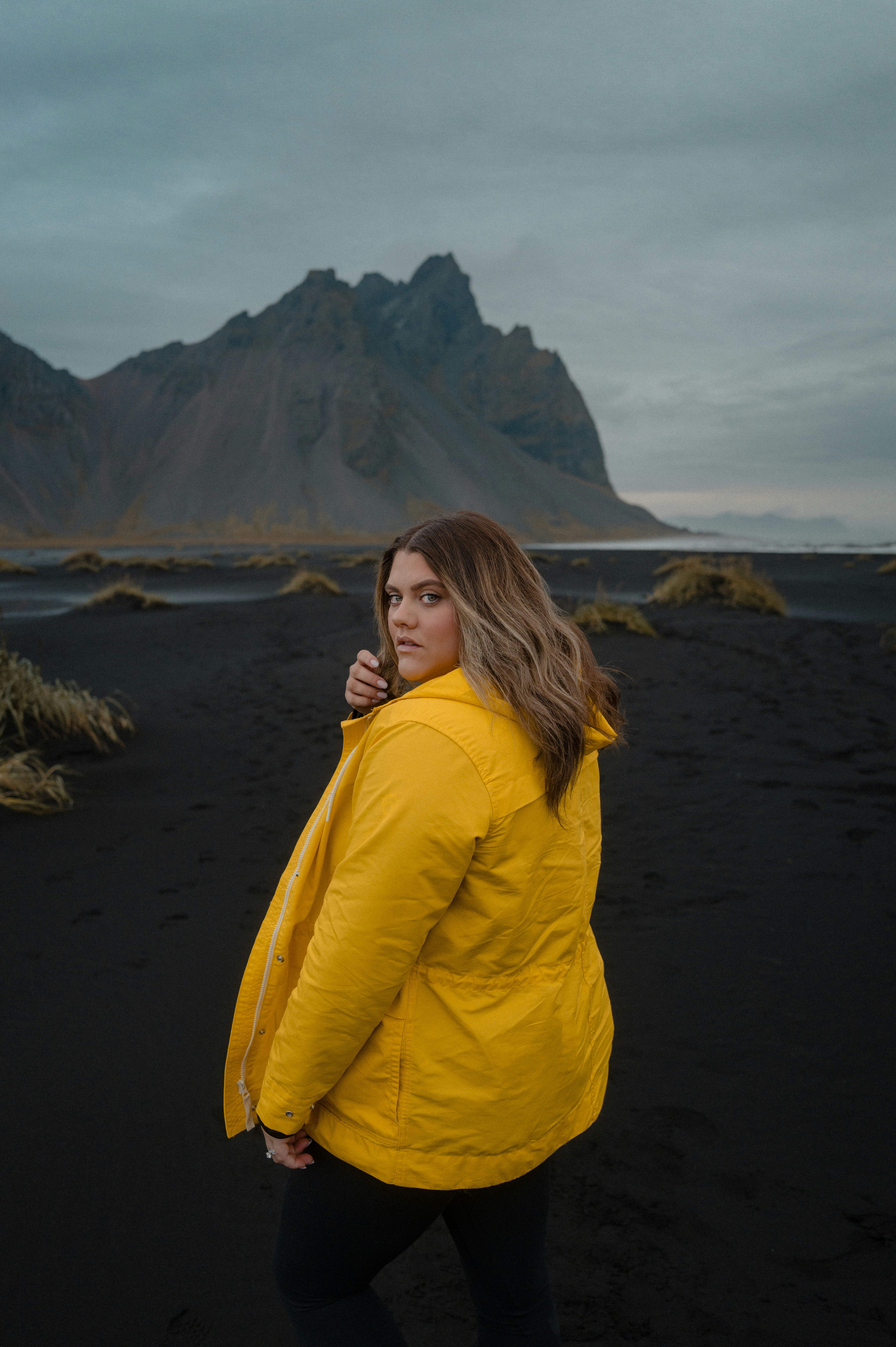 A woman in a yellow jacket standing on a beach
