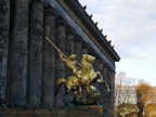 A statue of a man on a horse in front of a building