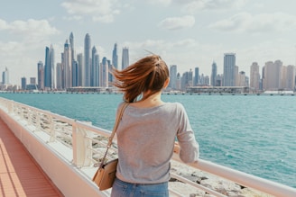 A woman standing on a bridge looking at the city