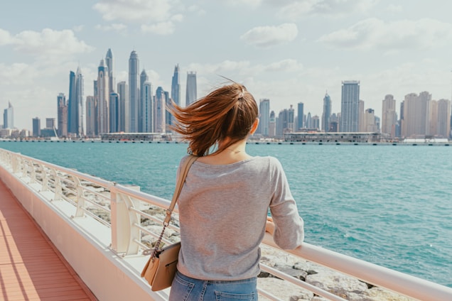 A woman standing on a bridge looking at the city