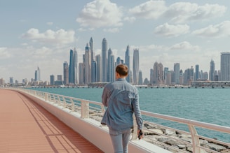 A man walking on a bridge with a city in the background