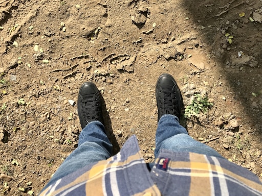A person standing in the dirt with their feet up