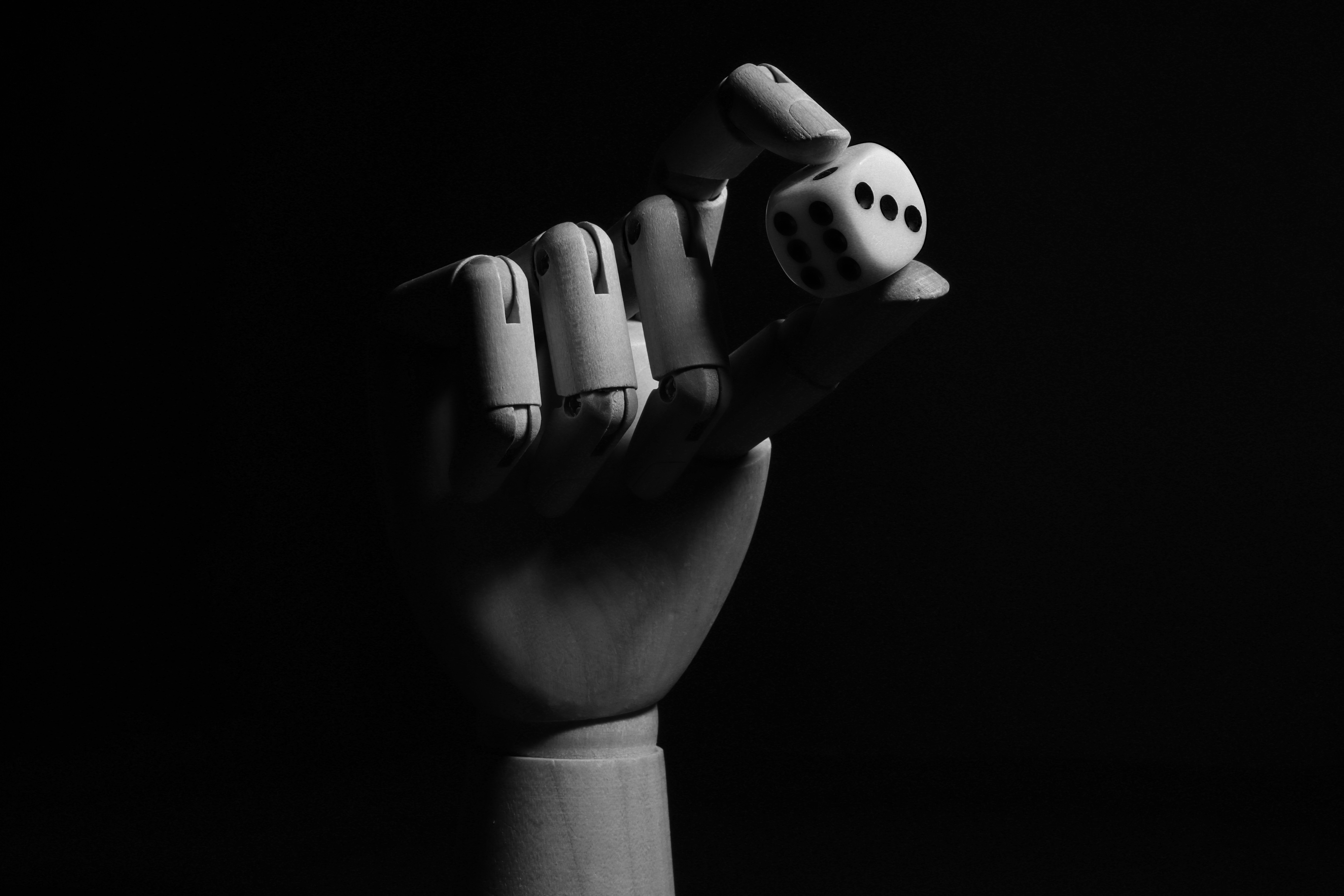 Alt text: Black and white photo of a hand holding a dice, Branimo branding