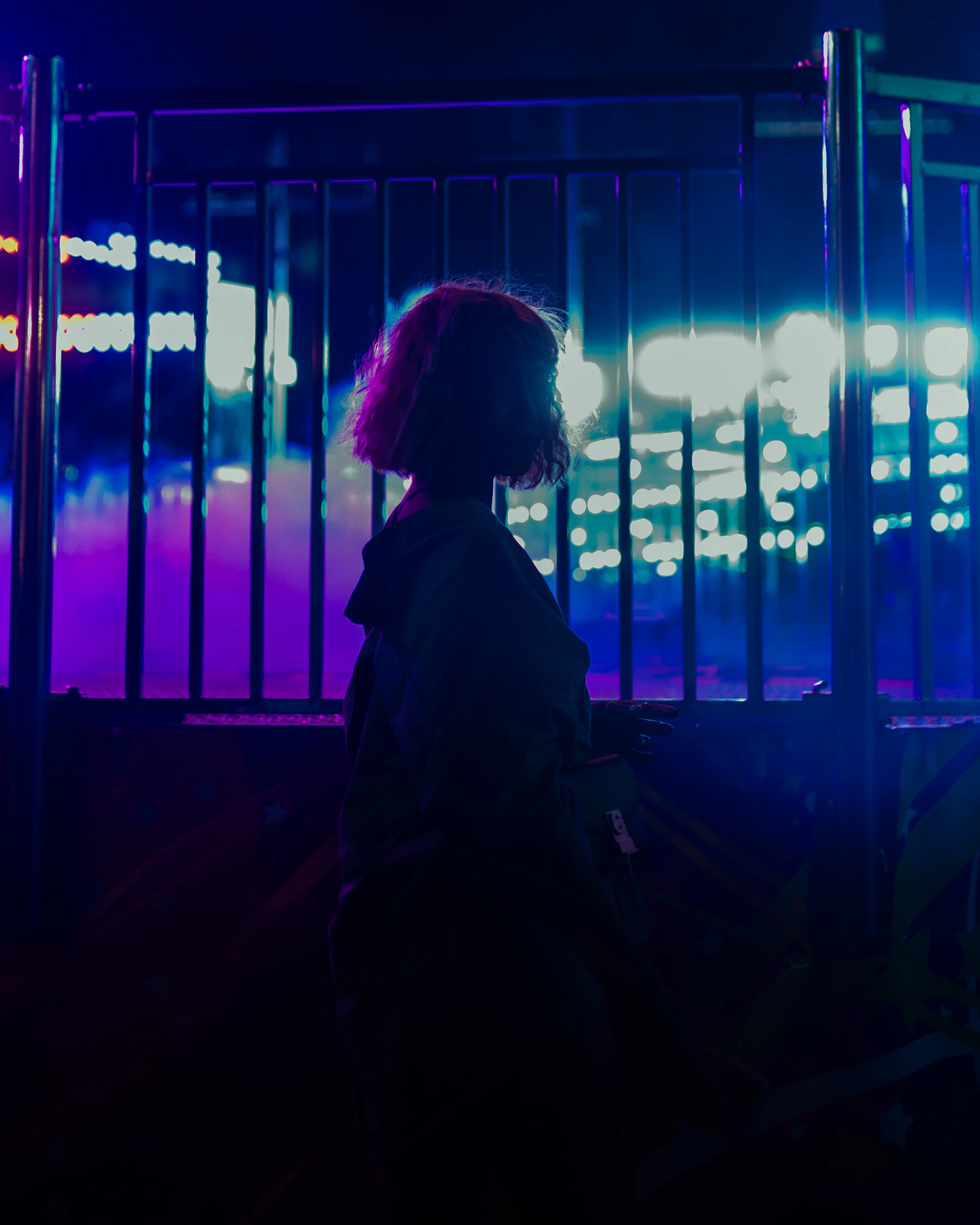 A person standing in front of a fence at night