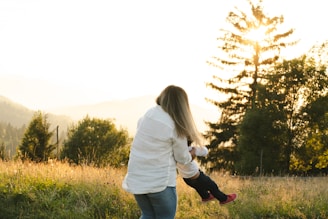 A woman holding a small child in a field