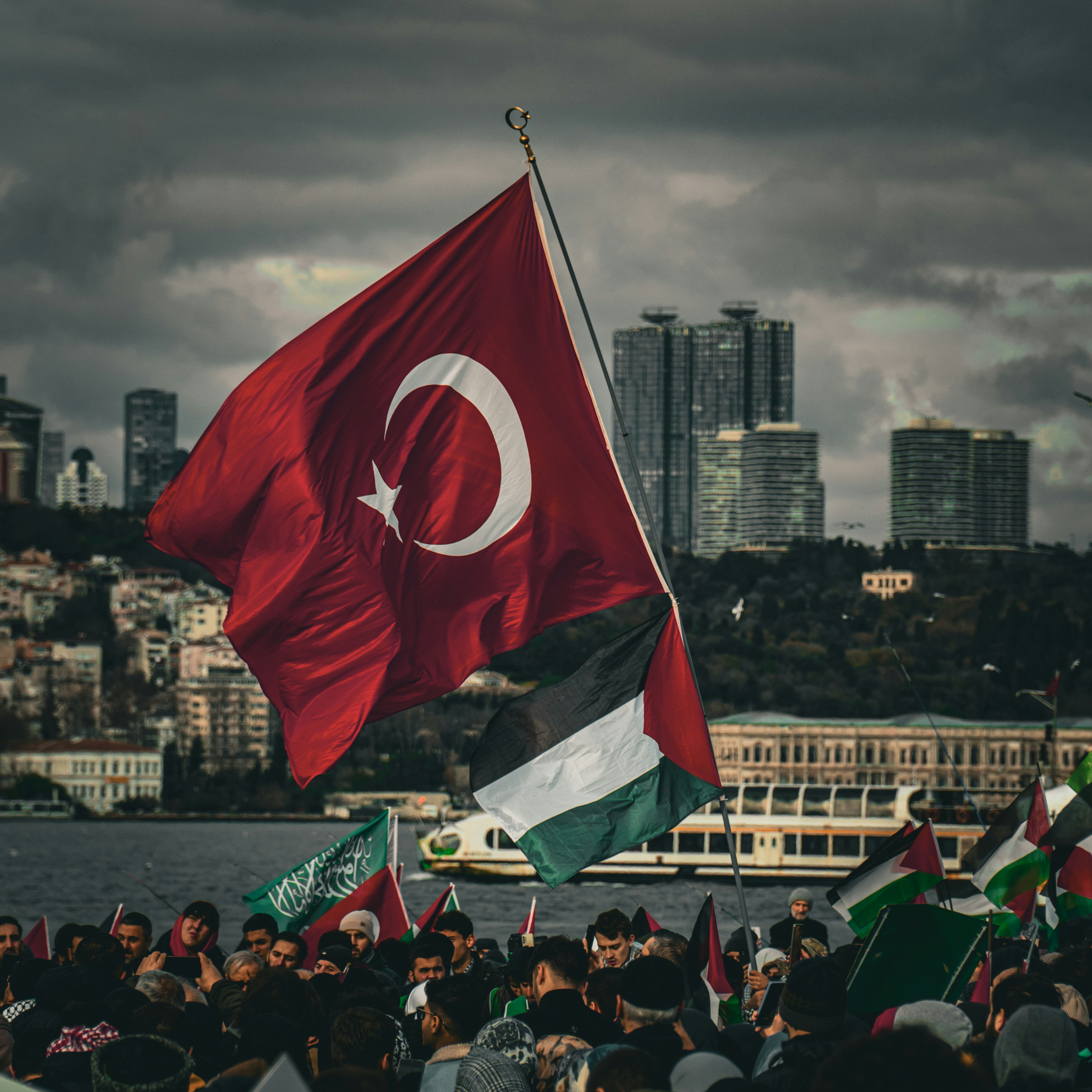 A group of people holding flags in front of a body of water