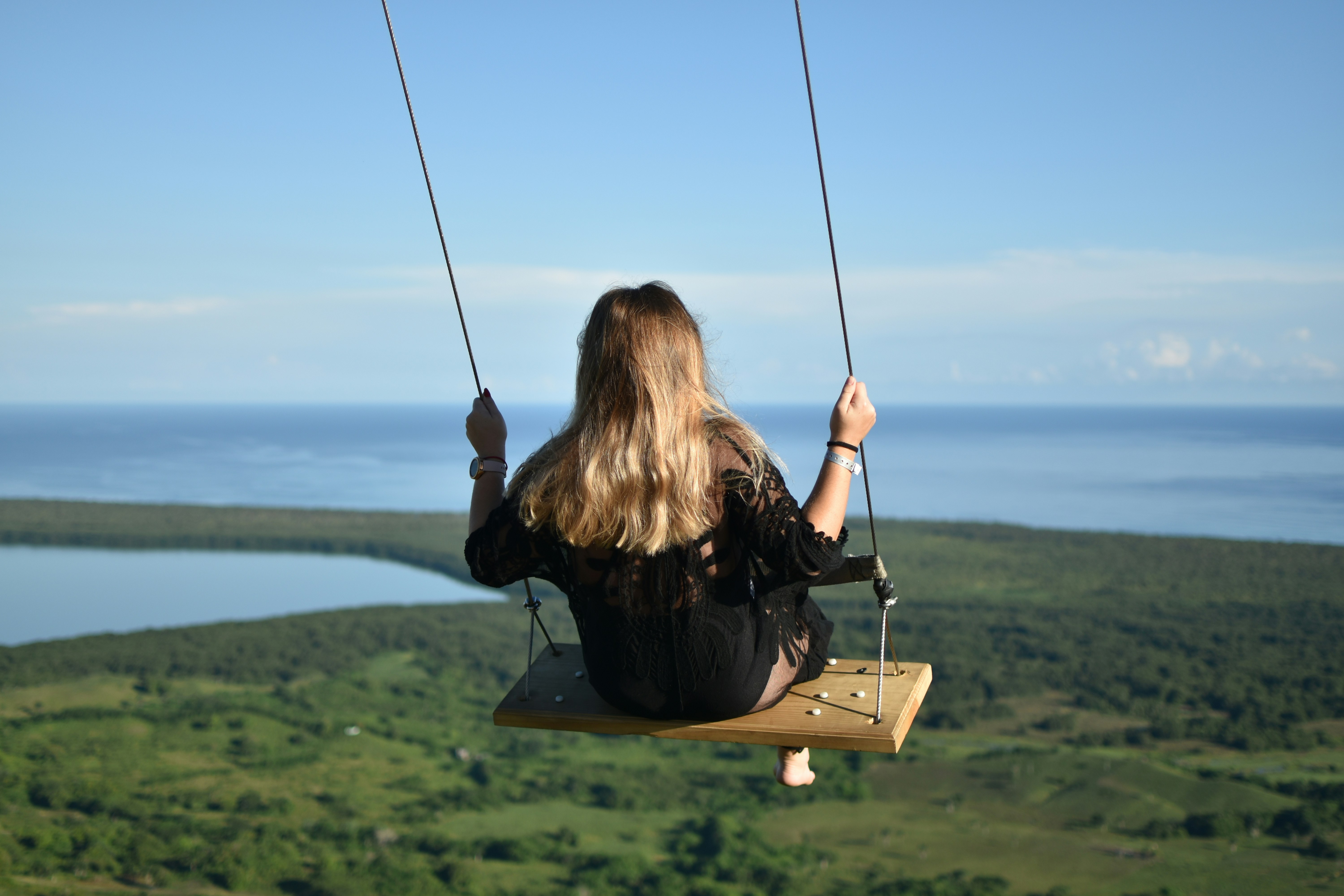 A woman sitting on a swing overlooking the ocean