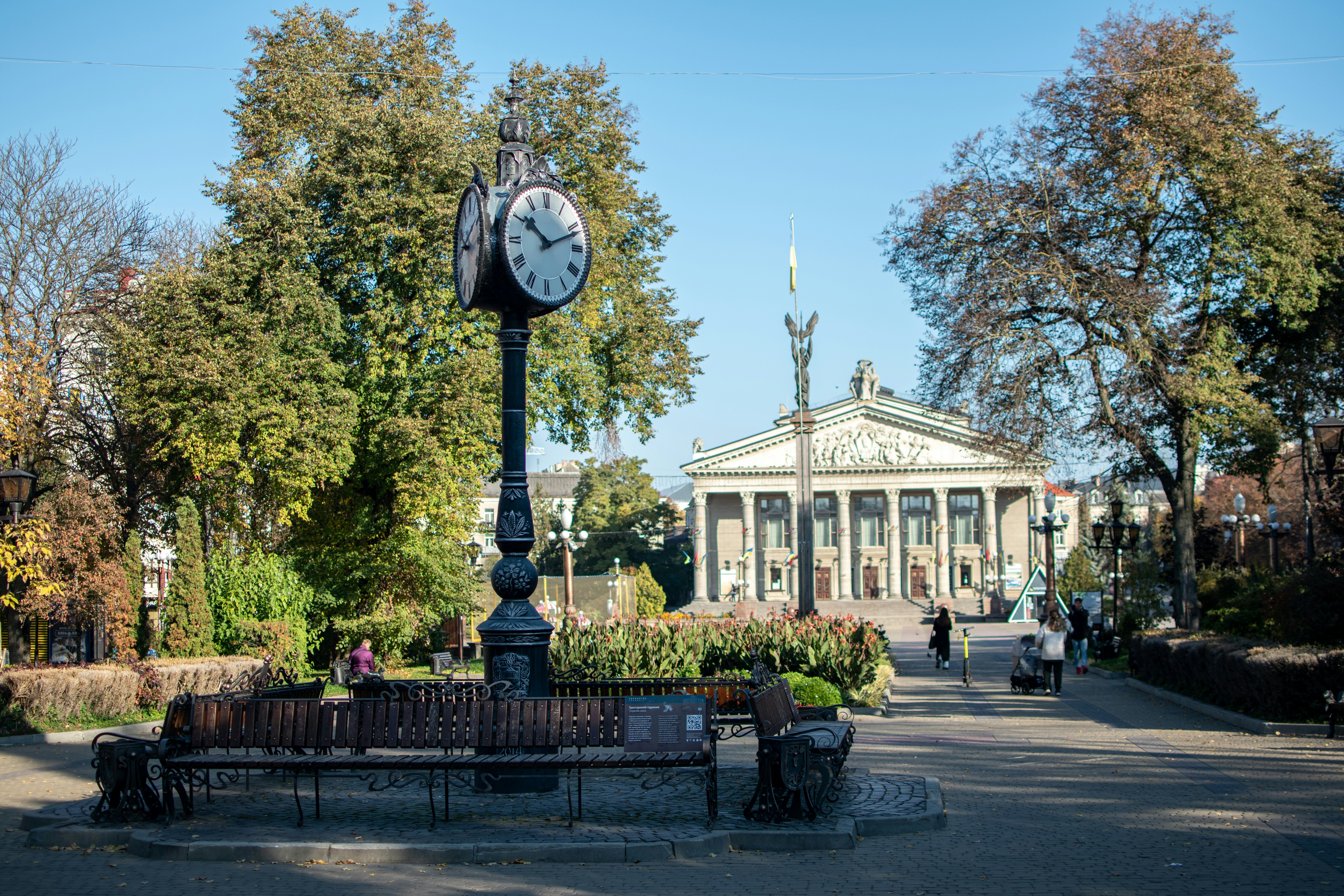 A clock on a pole in the middle of a park