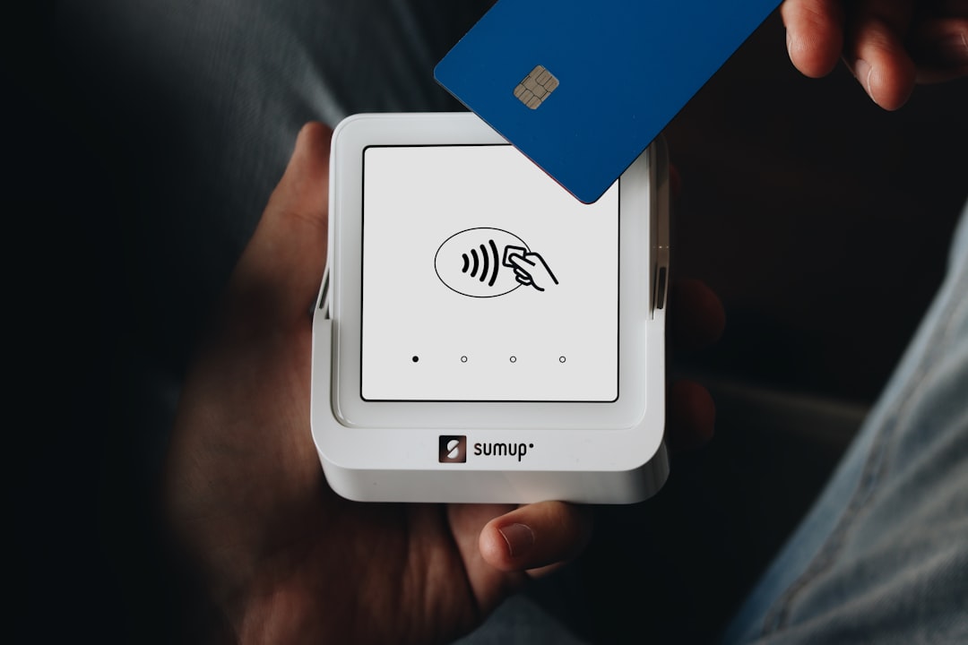 A person holding a credit card in their hand, SumUp card reader showcasing contactless payment capabilities with the Sum