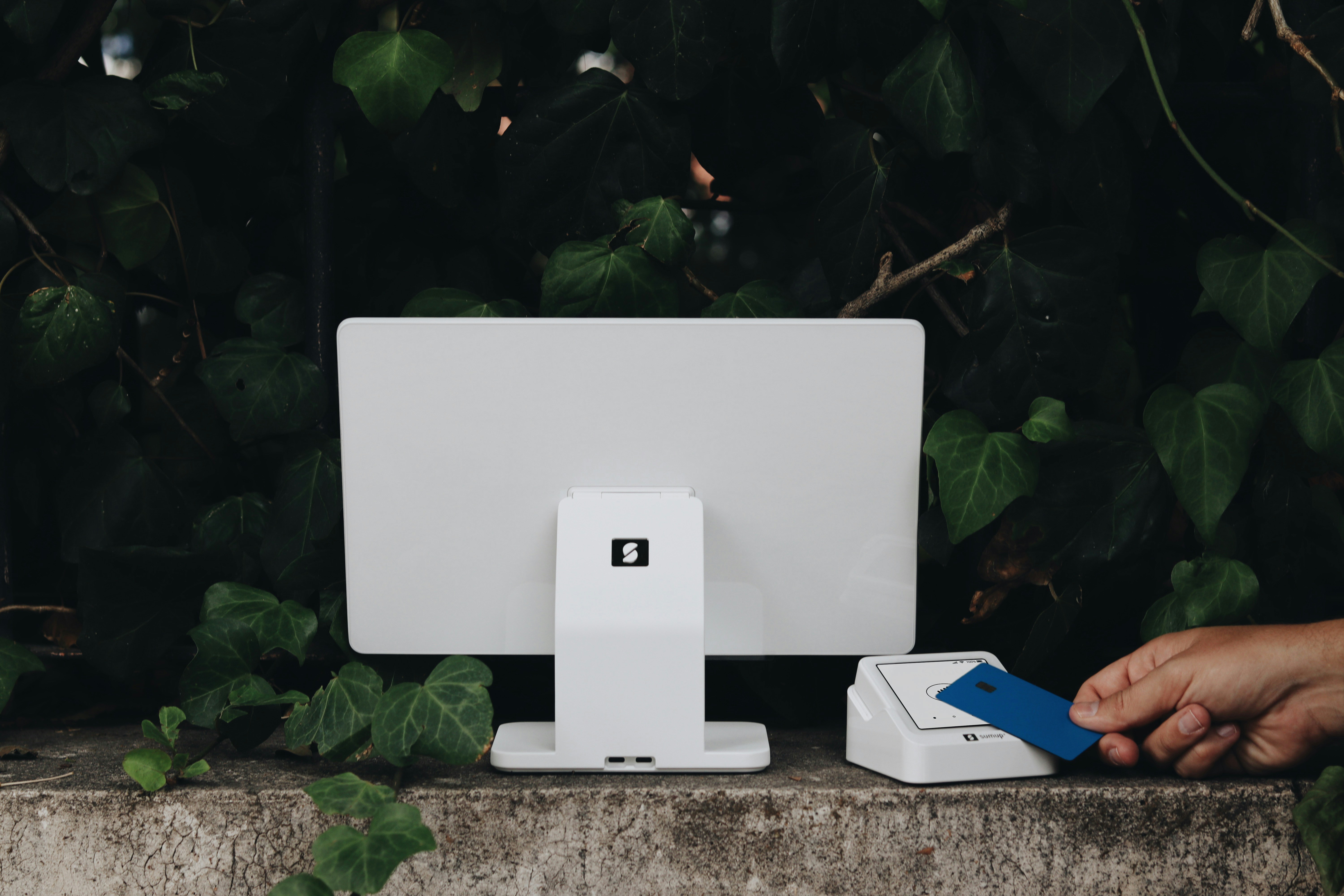 A person holding a blue and white object near a computer