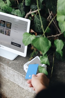 A person holding a credit card next to a computer