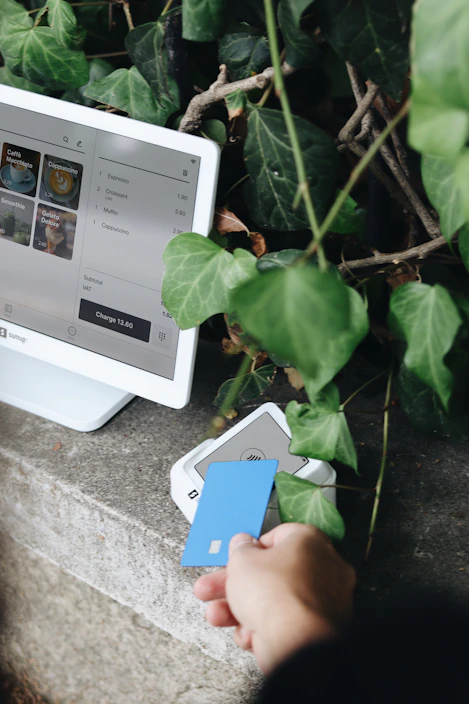 A person holding a credit card next to a computer