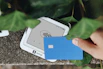 A hand holding a credit card next to a cell phone