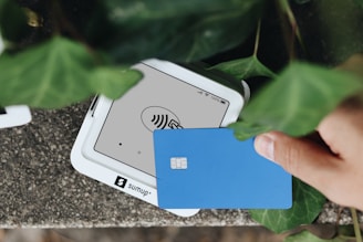 A hand holding a credit card next to a cell phone