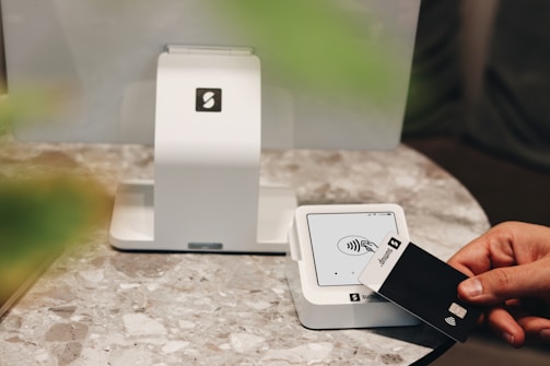 A person holding a credit card in front of a computer