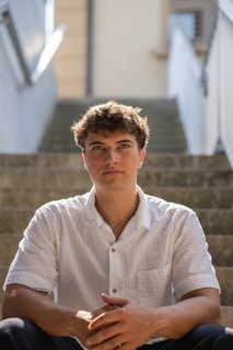 A young man sitting on the steps of a building