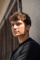 A young man standing next to a building