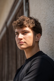 A young man standing next to a building