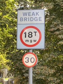 A street sign on a pole in front of some trees