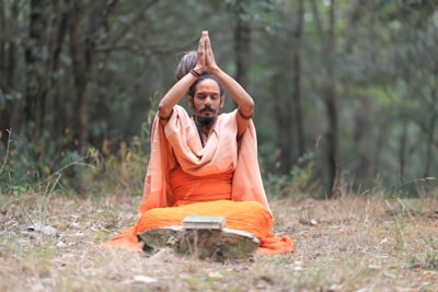 A man sitting in the middle of a forest doing yoga