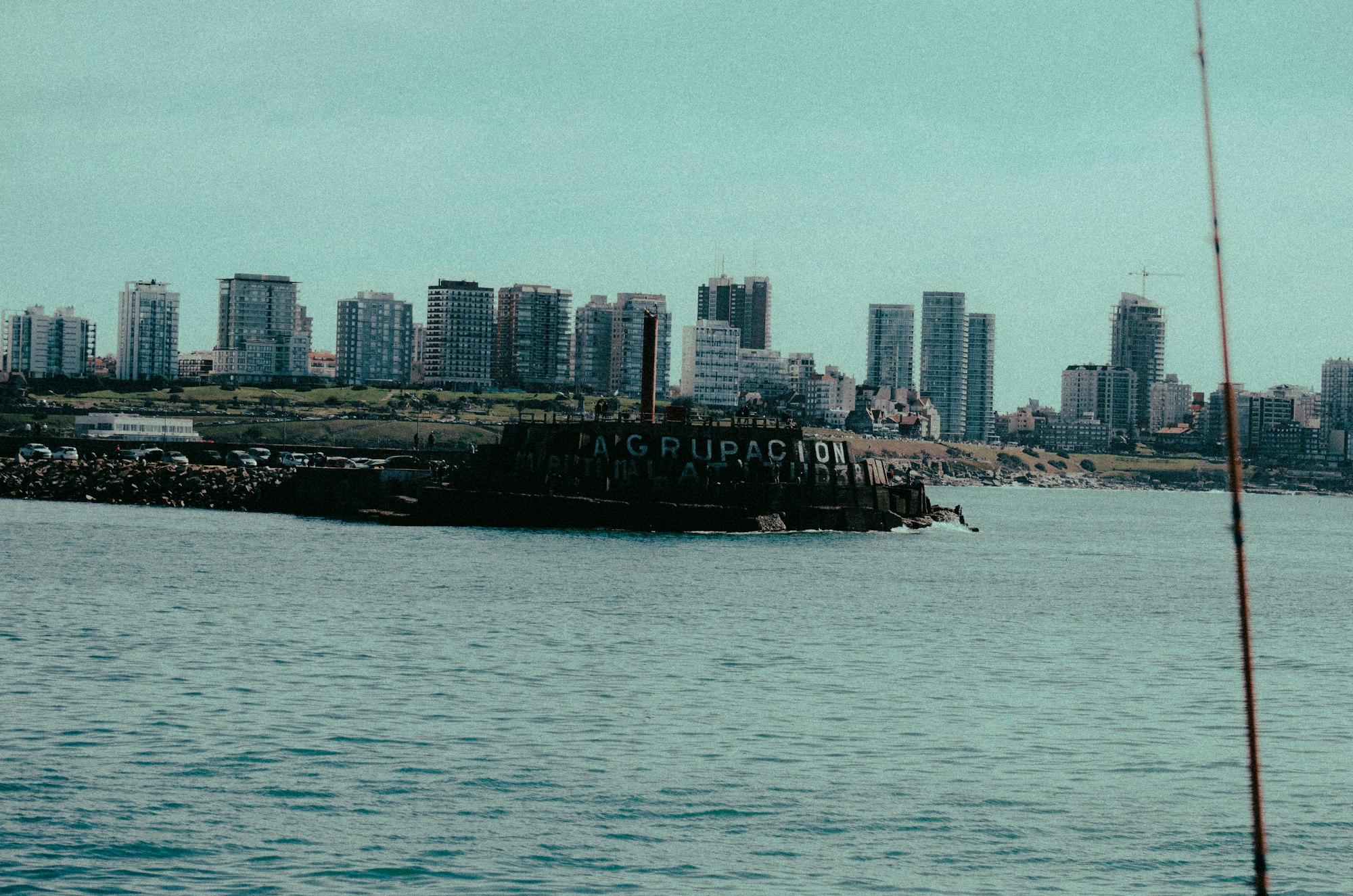 A man fishing in the water with a city in the background