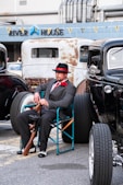 A man sitting in a chair next to a black car