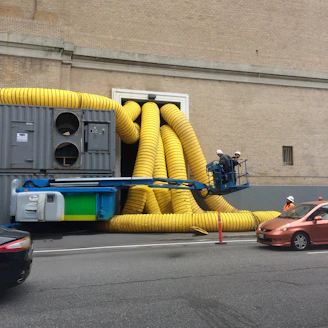A truck with a yellow hose attached to it driving down a street