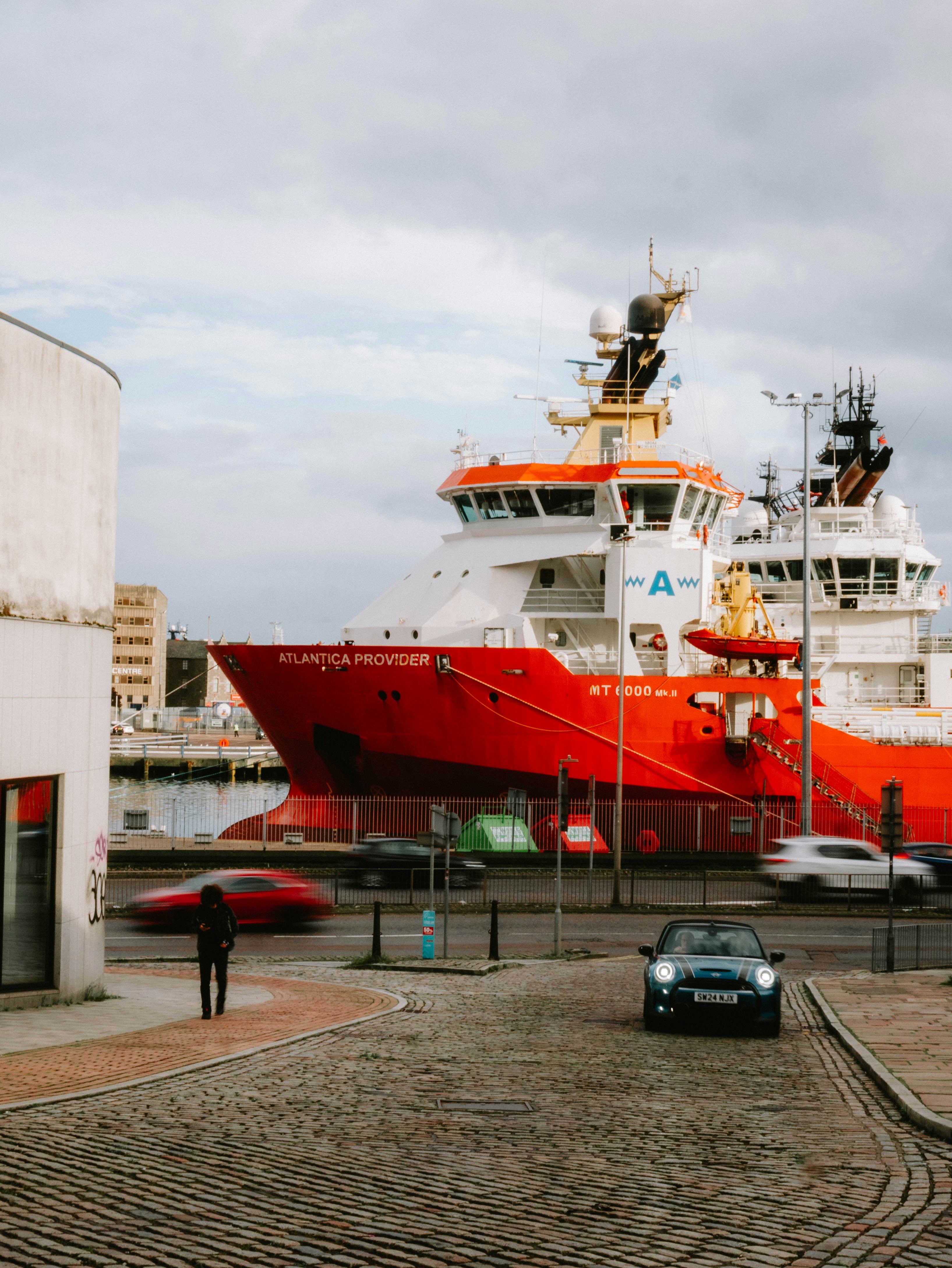 A red and white boat in a harbor next to a building