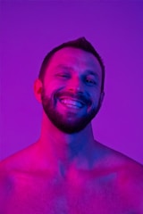 A shirtless man with no shirt on in front of a purple background