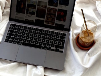 An open laptop computer sitting on top of a bed