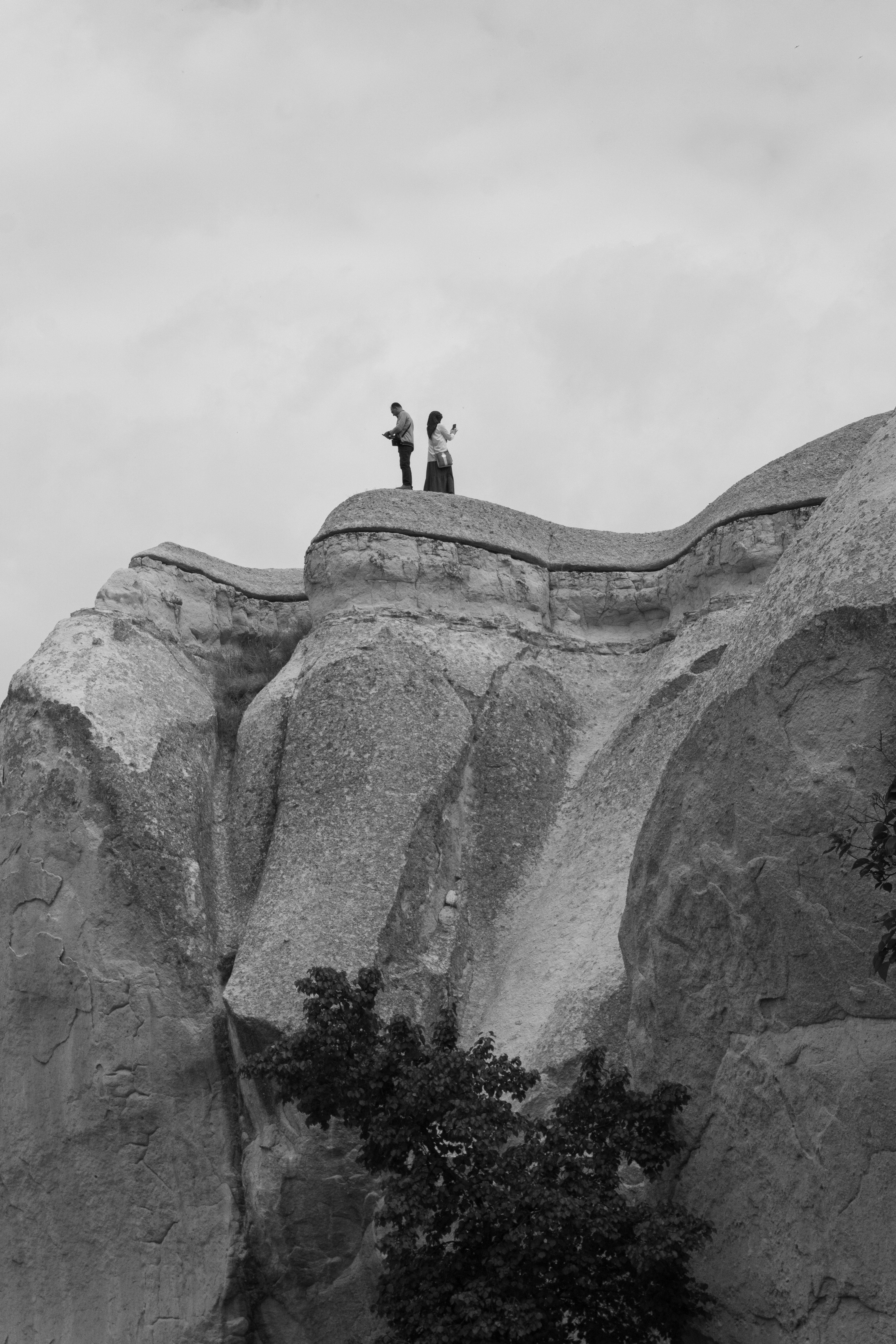 A couple of people standing on top of a large rock photo – Free ...