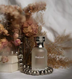 A bottle of perfume sitting next to a vase of flowers