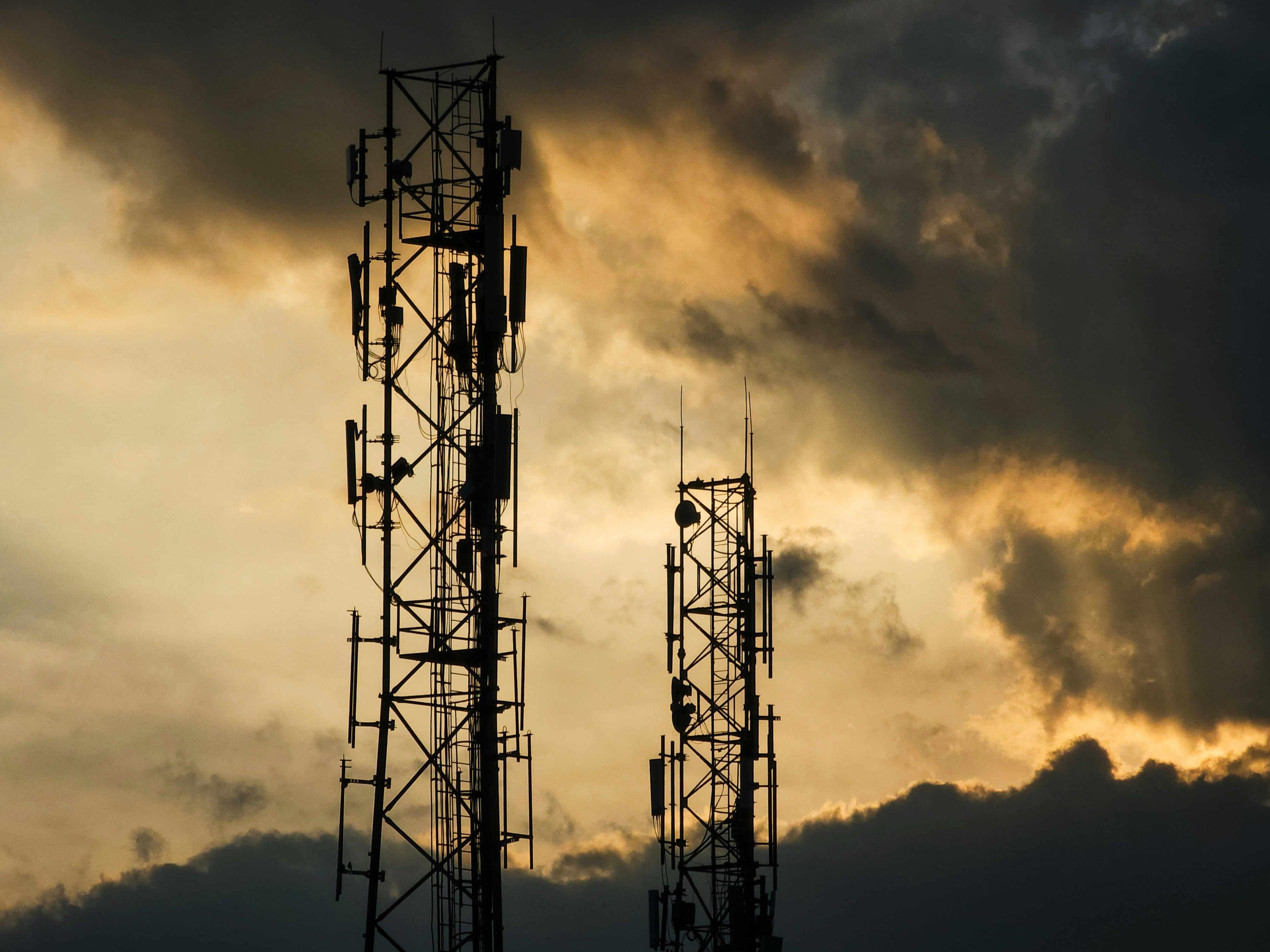 A couple of cell towers sitting under a cloudy sky