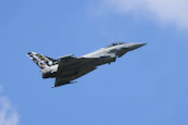 A fighter jet flying through a blue sky