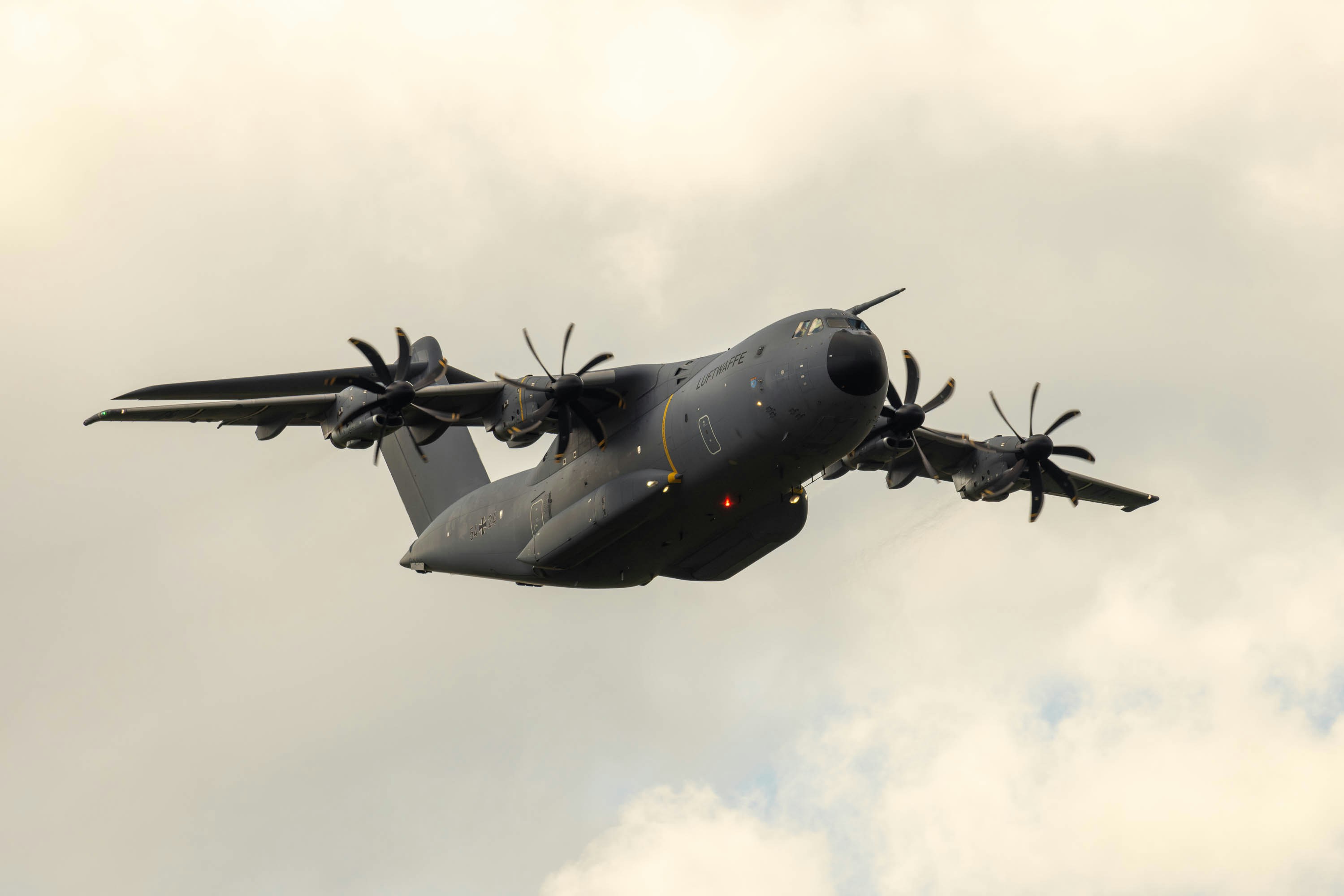A large air plane flying through a cloudy sky