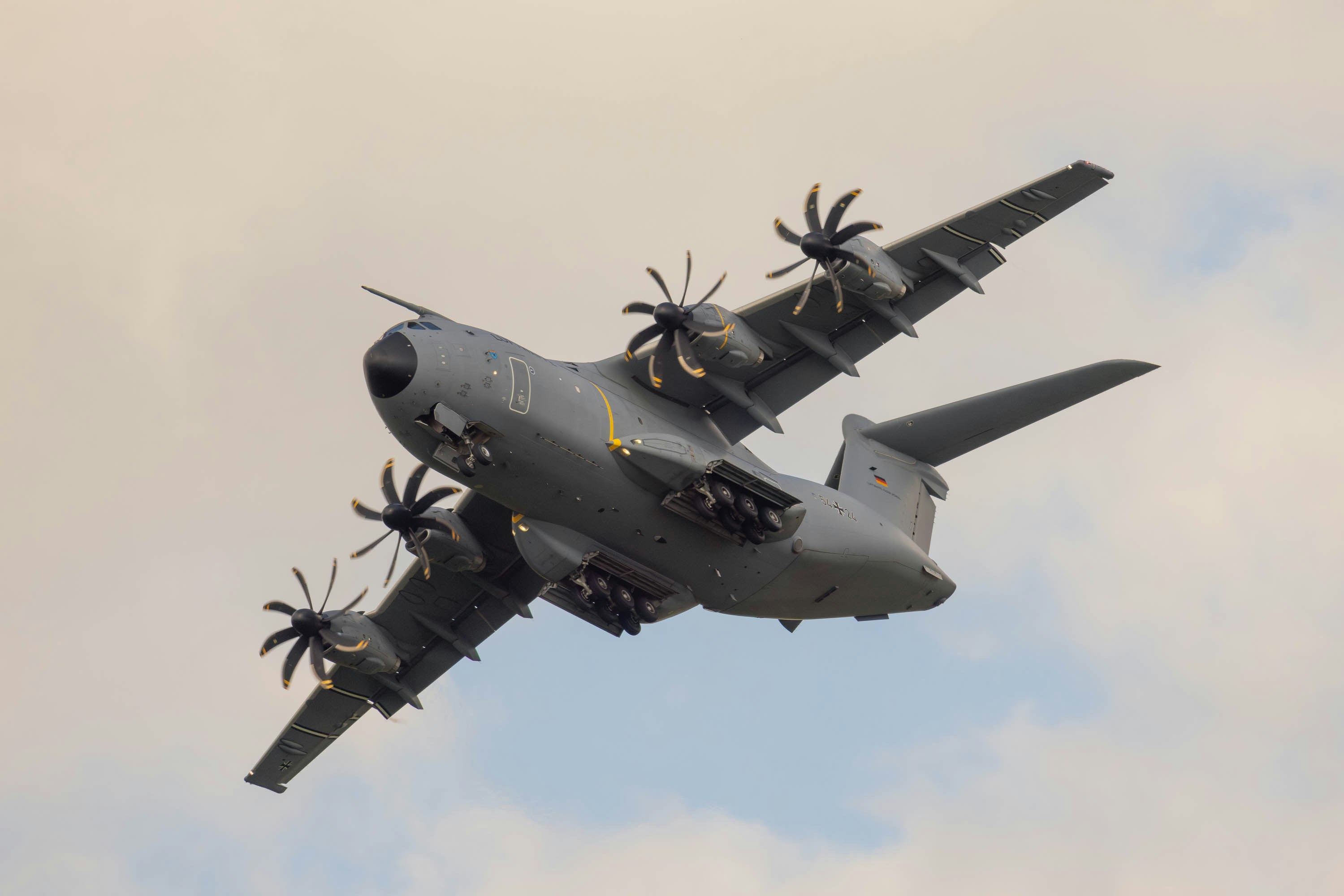 A large military plane flying through a cloudy sky