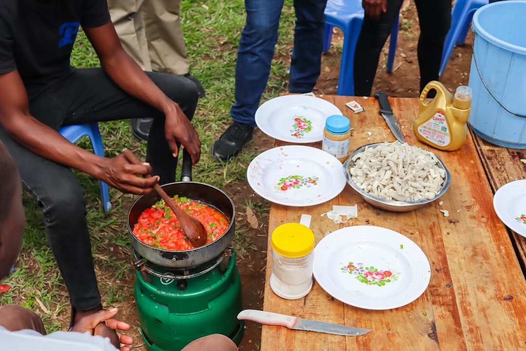 A group of people sitting around a wooden table, cooking mushroom