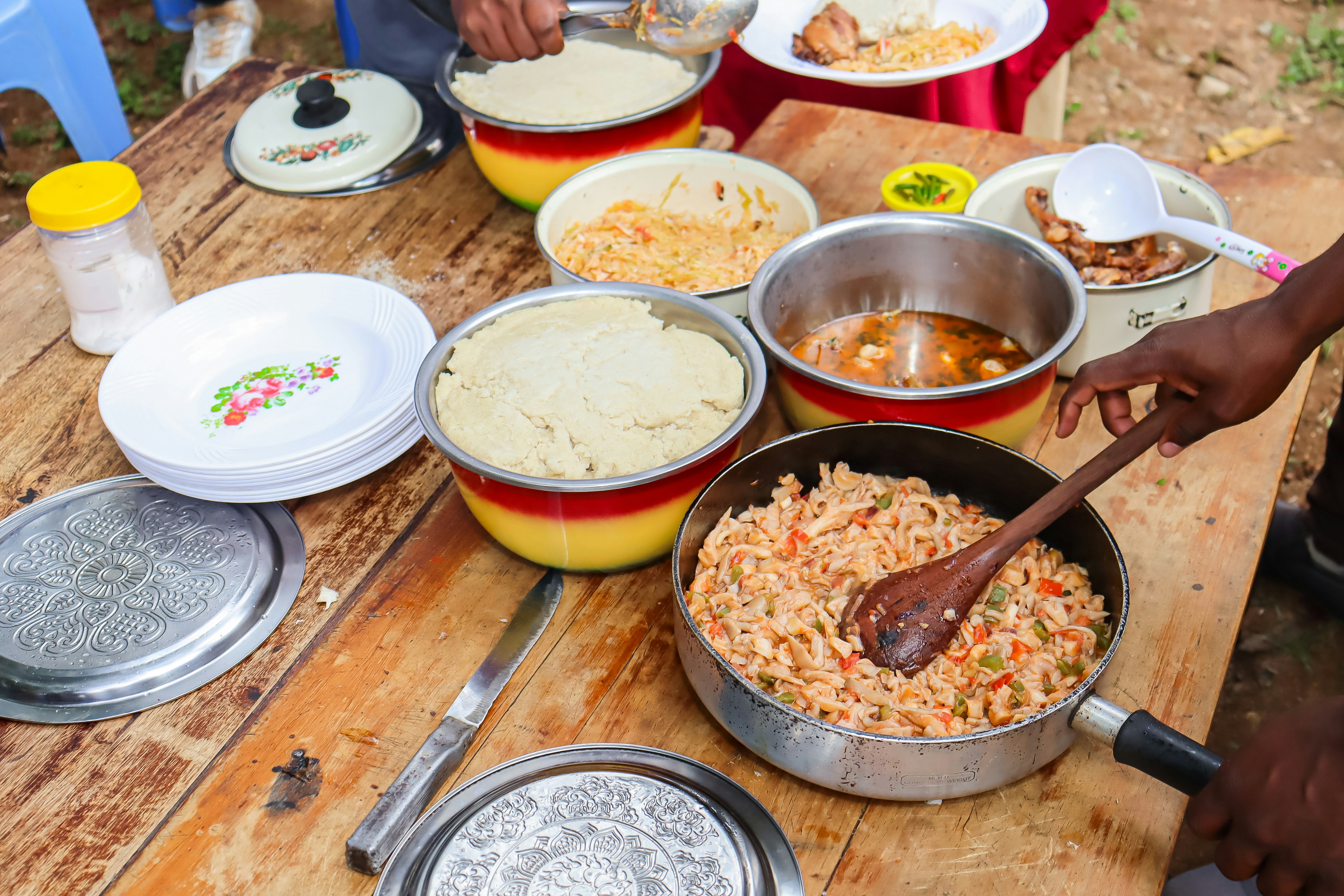 a wooden table with bowls and pans filled with food
