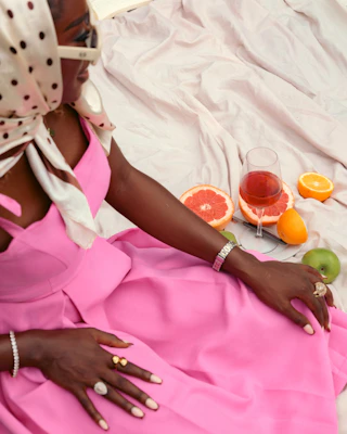 A woman in a pink dress sitting on a bed
