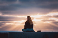 A woman sitting on a wall looking at the sky