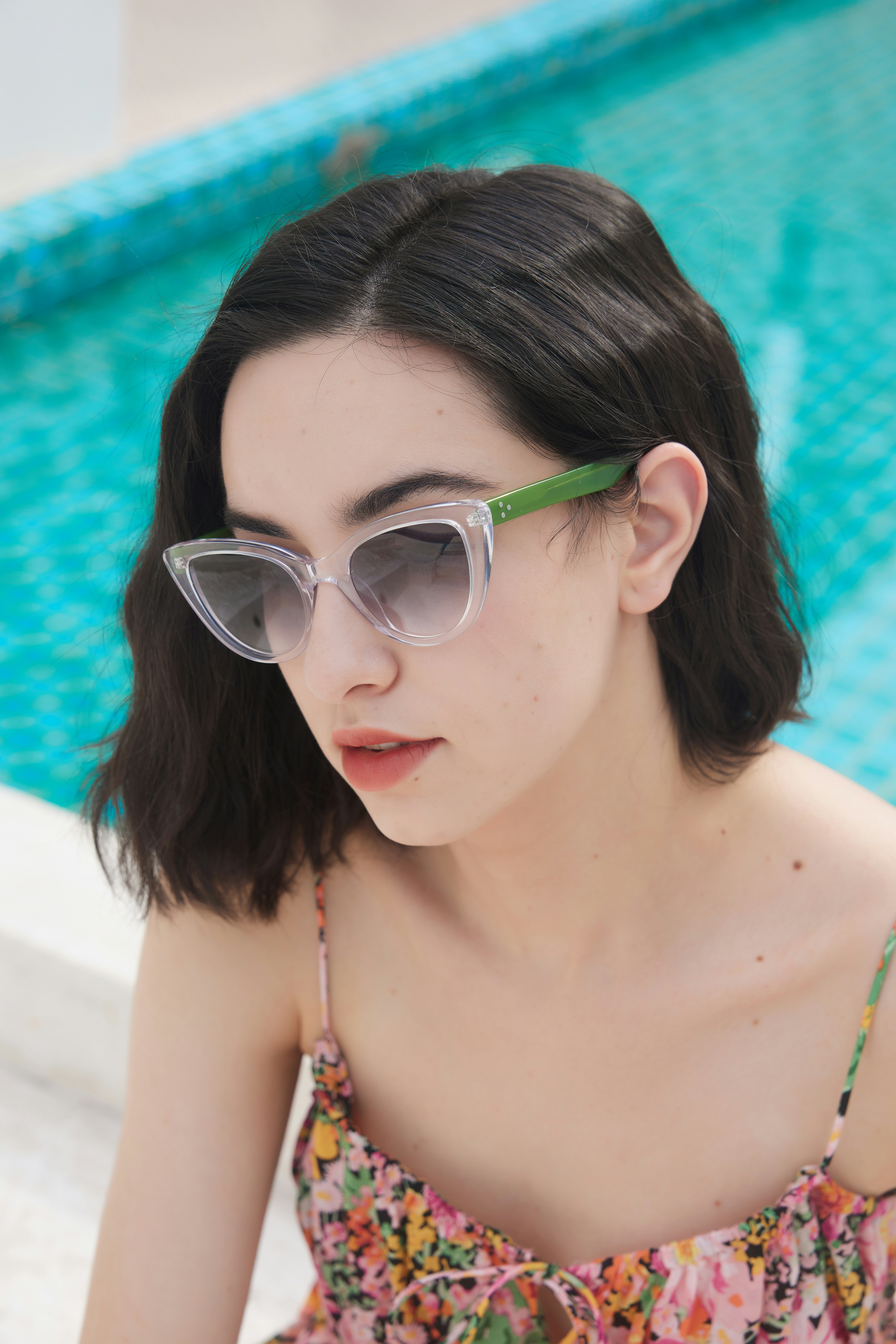A woman sitting next to a pool wearing sunglasses