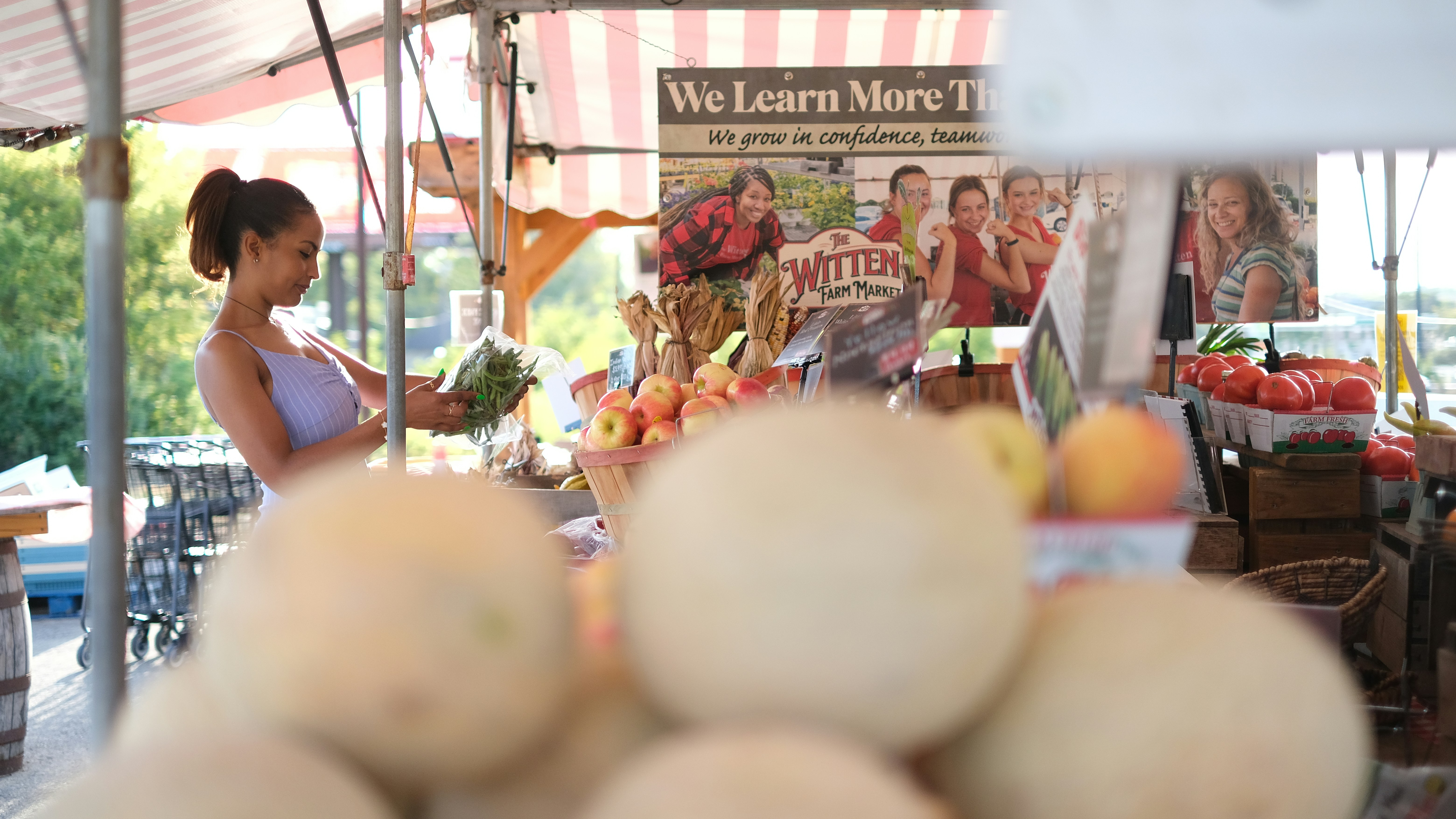 A woman is standing in front of a fruit stand