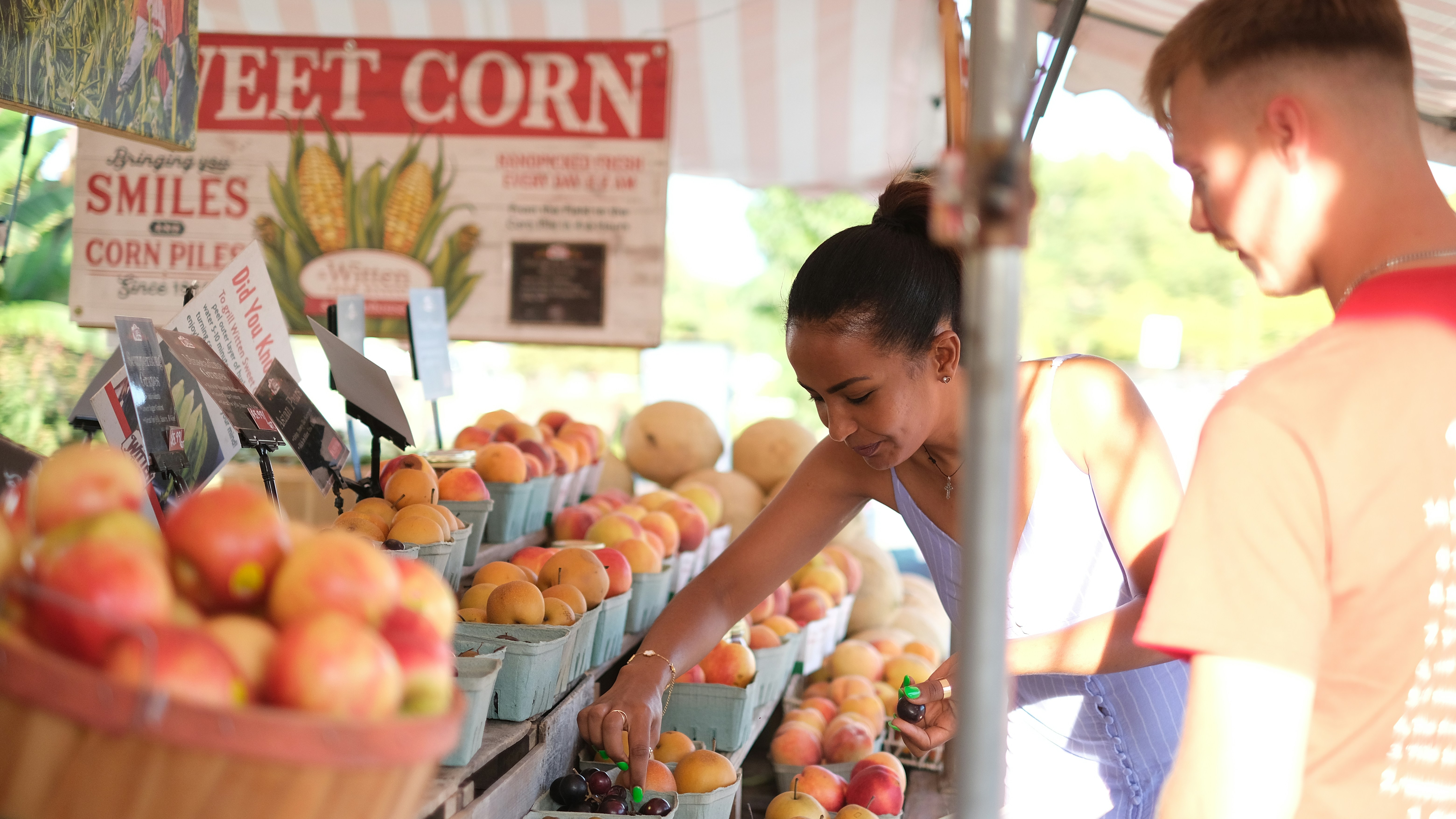 A man and a woman standing in front of a fruit stand
