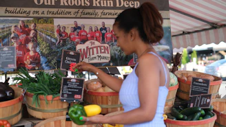 A woman standing in front of a display of fruits and vegetables