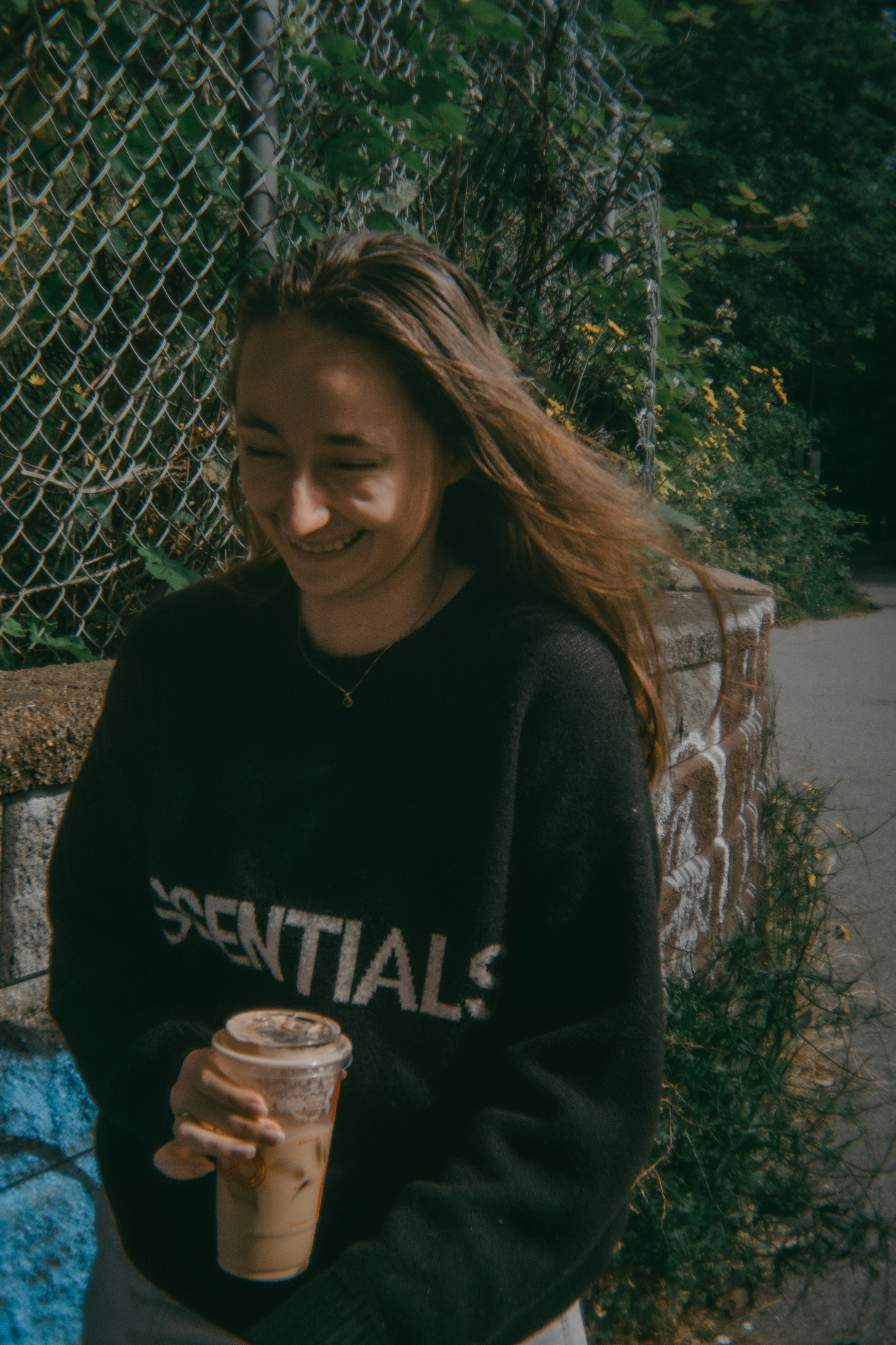 A woman sitting on a bench holding a cup of coffee