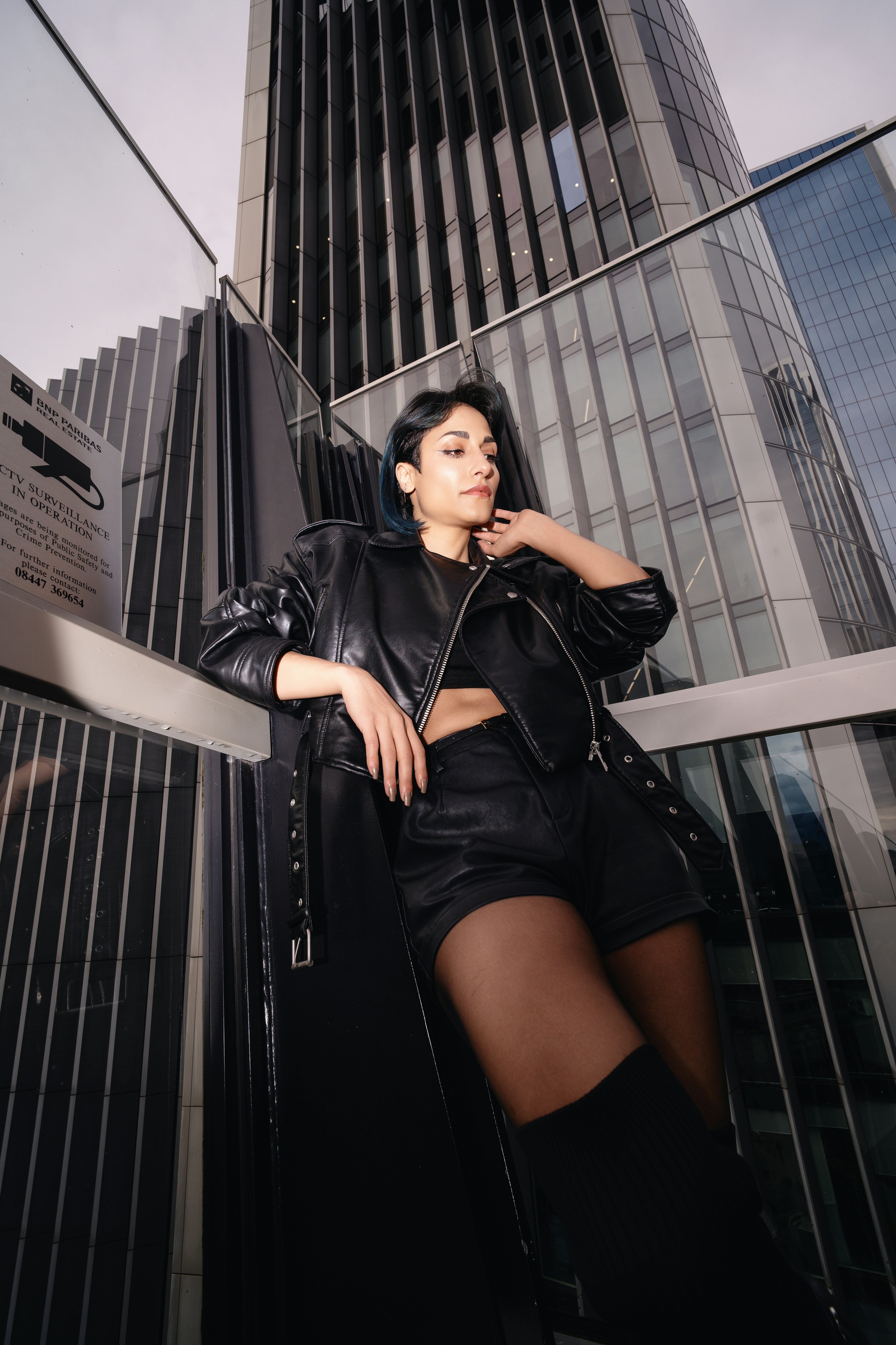 A woman leaning against a wall in front of a tall building