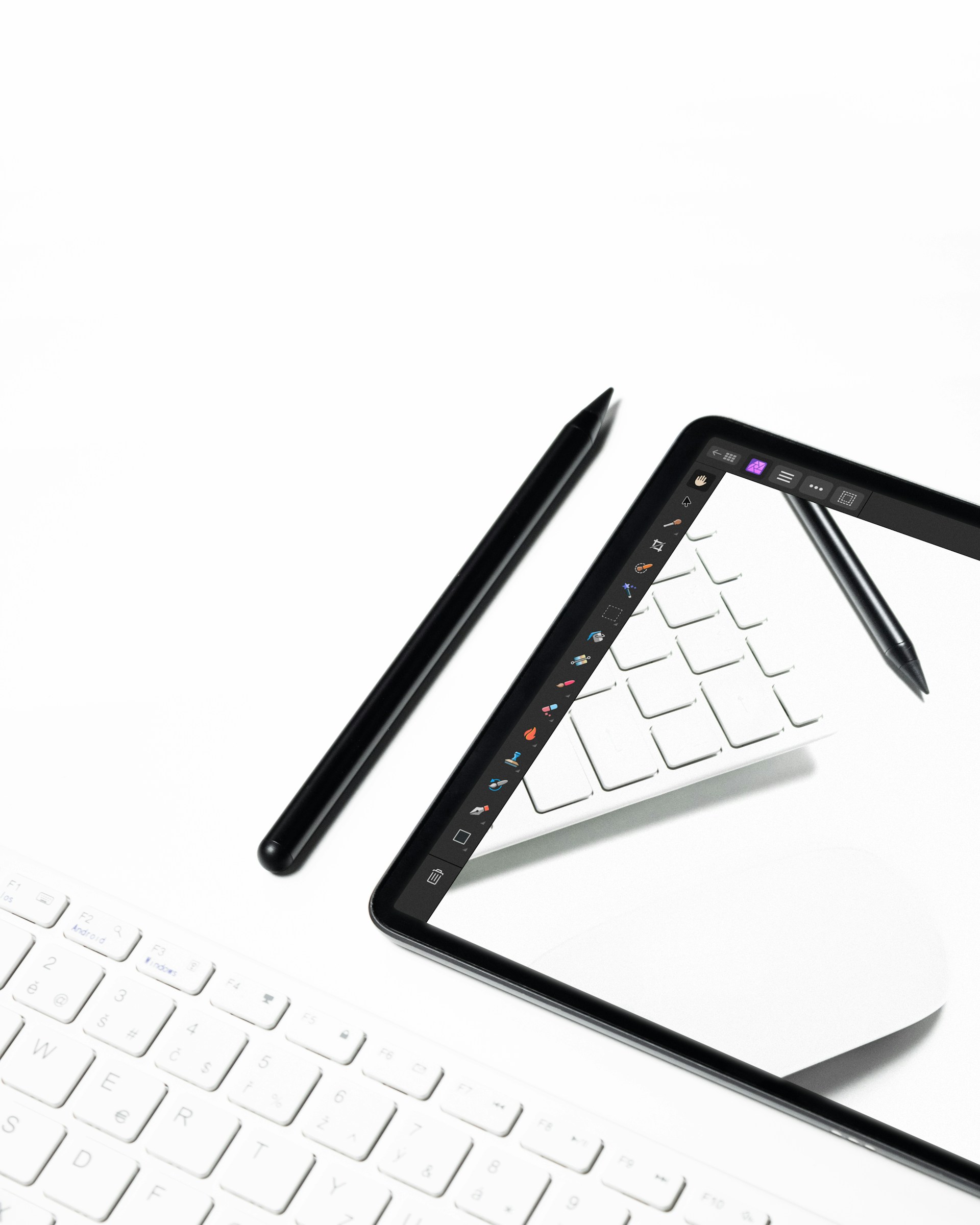 A tablet and a keyboard on a white surface