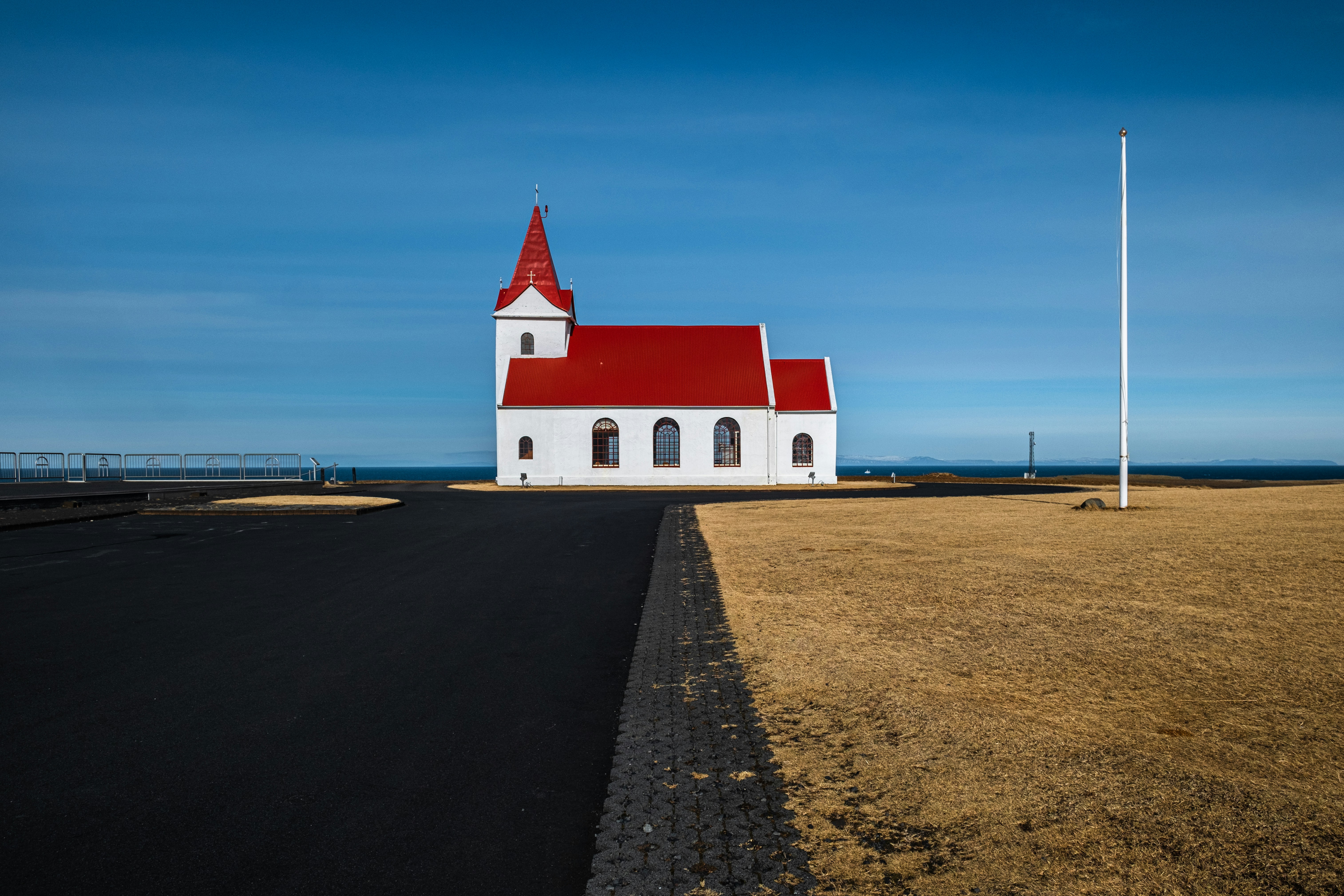 A white church with a red roof on the side of a road
