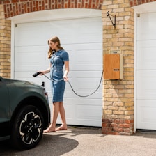 A woman in a blue dress is washing a car