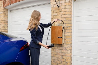 A woman in a business suit using an EV charger